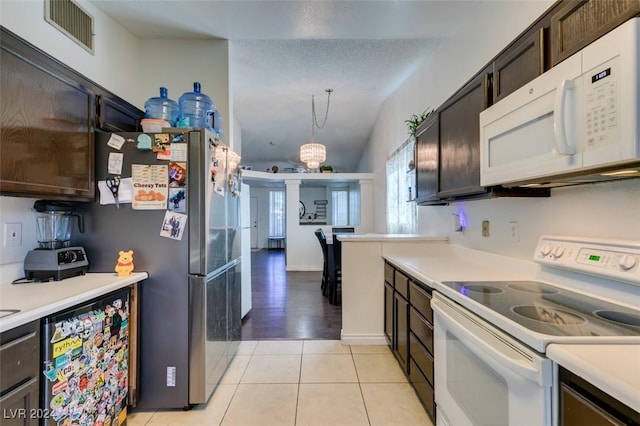 kitchen featuring light tile patterned flooring, decorative light fixtures, white appliances, dark brown cabinetry, and a textured ceiling