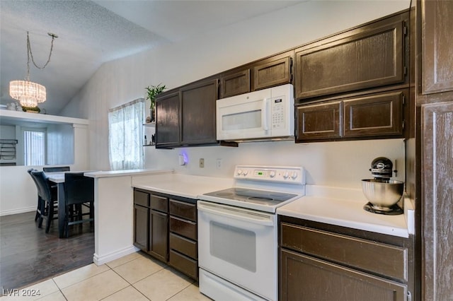 kitchen featuring lofted ceiling, light tile patterned floors, white appliances, hanging light fixtures, and a chandelier