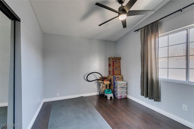 miscellaneous room featuring ceiling fan, a wealth of natural light, dark wood-type flooring, and a textured ceiling