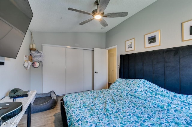 bedroom with lofted ceiling, ceiling fan, a closet, and a textured ceiling