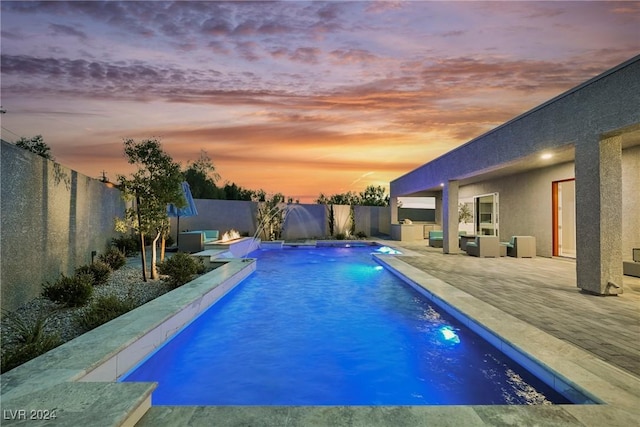 pool at dusk with pool water feature, an outdoor living space, and a patio area