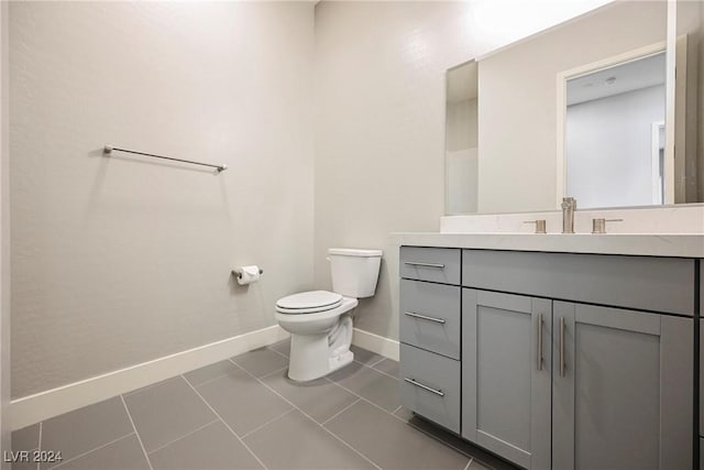 bathroom with toilet, vanity, and tile patterned floors