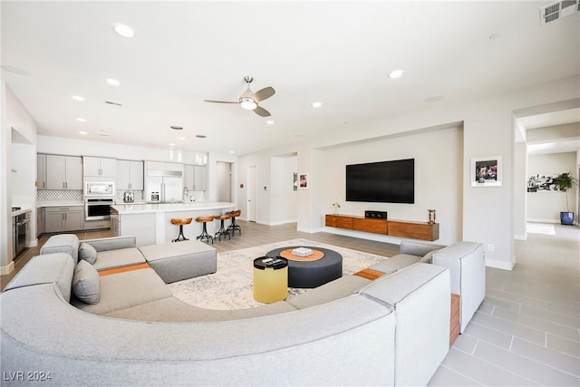 living room with ceiling fan, light tile patterned floors, and sink