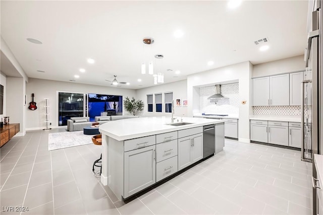 kitchen with backsplash, ceiling fan, sink, dishwasher, and an island with sink