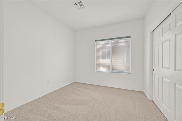 unfurnished bedroom featuring light carpet and a closet