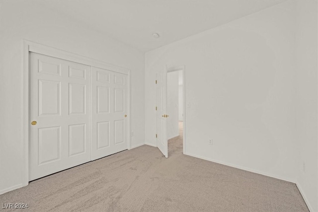 unfurnished bedroom with a closet and light colored carpet