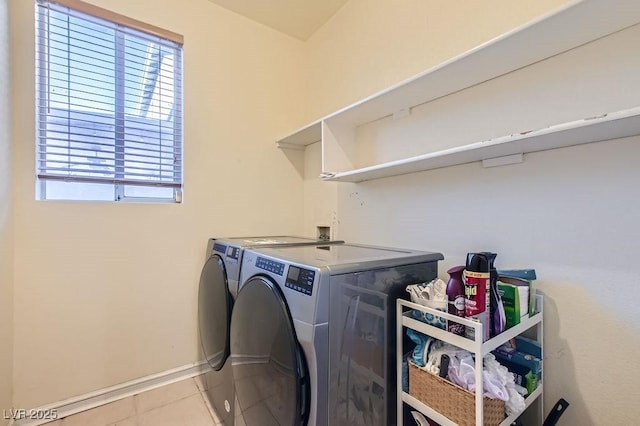 washroom with light tile patterned floors, laundry area, separate washer and dryer, and baseboards