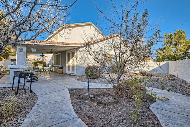 rear view of house with ceiling fan and a patio area