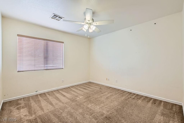 carpeted spare room featuring baseboards, visible vents, and a ceiling fan