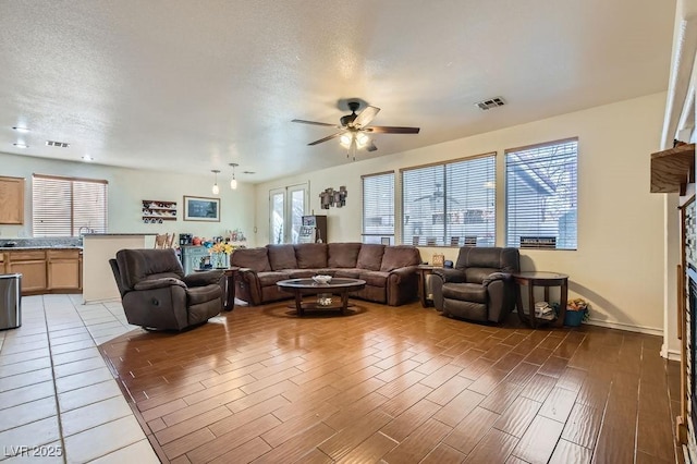 living room with light wood-type flooring, a fireplace, and visible vents