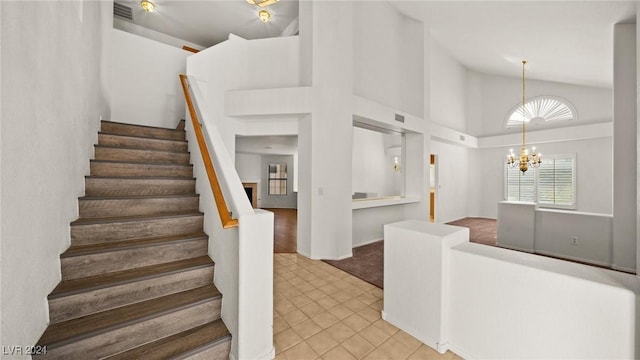 stairs featuring tile patterned flooring, high vaulted ceiling, and a chandelier