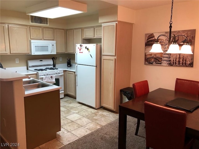 kitchen featuring white appliances, sink, hanging light fixtures, light tile patterned floors, and a chandelier