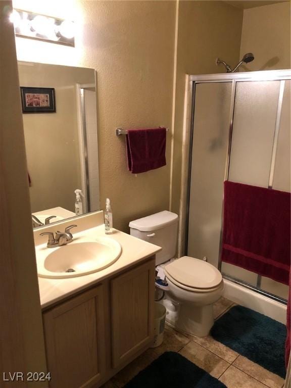 bathroom featuring tile patterned floors, toilet, a shower with door, and vanity