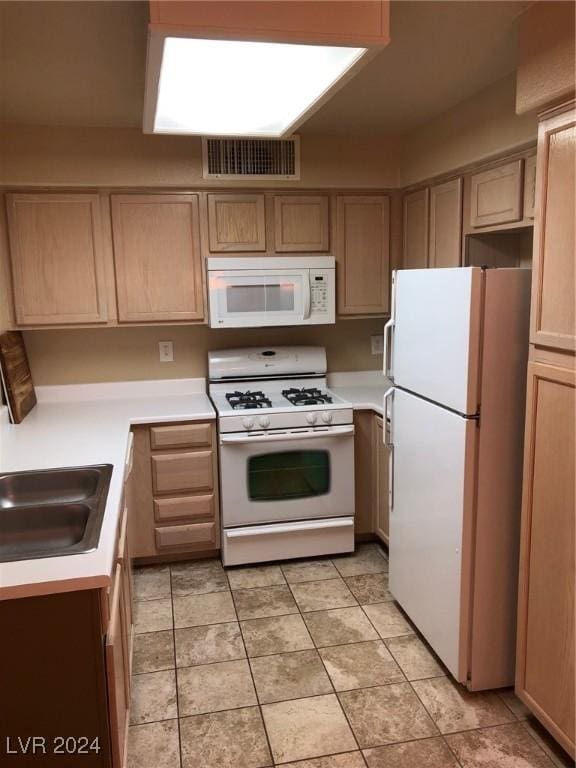 kitchen featuring sink, light brown cabinets, white appliances, and light tile patterned floors