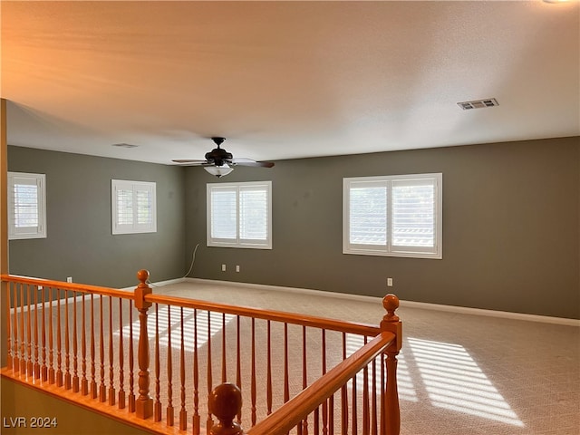 carpeted spare room featuring ceiling fan and plenty of natural light