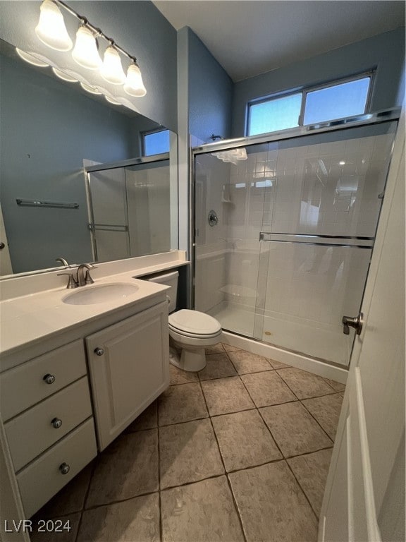 bathroom featuring tile patterned floors, vanity, toilet, and a shower with shower door