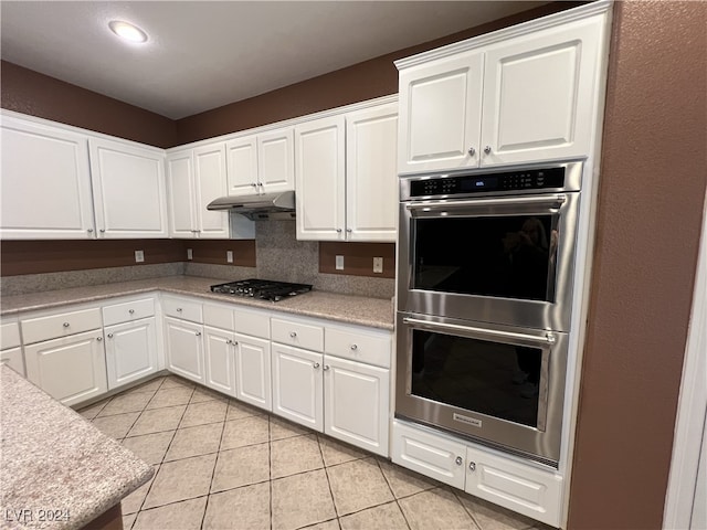 kitchen featuring light tile patterned flooring, decorative backsplash, white cabinets, and stainless steel appliances