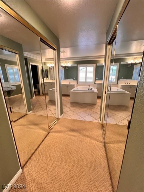 bathroom featuring a washtub, vanity, a textured ceiling, and tile patterned flooring