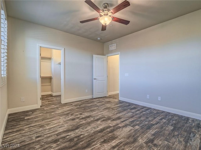 unfurnished bedroom featuring ceiling fan, a spacious closet, a closet, and dark hardwood / wood-style floors