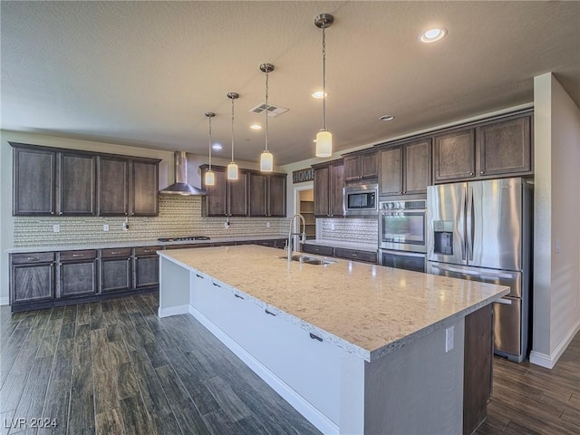 kitchen with stainless steel appliances, sink, an island with sink, light stone countertops, and pendant lighting