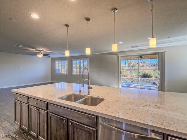 kitchen with sink, dishwasher, pendant lighting, and light stone countertops