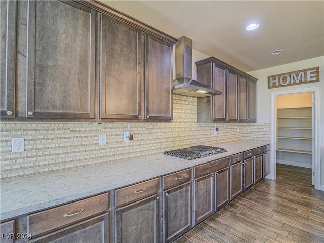 kitchen featuring light stone counters, wall chimney exhaust hood, stainless steel gas stovetop, dark hardwood / wood-style flooring, and dark brown cabinets