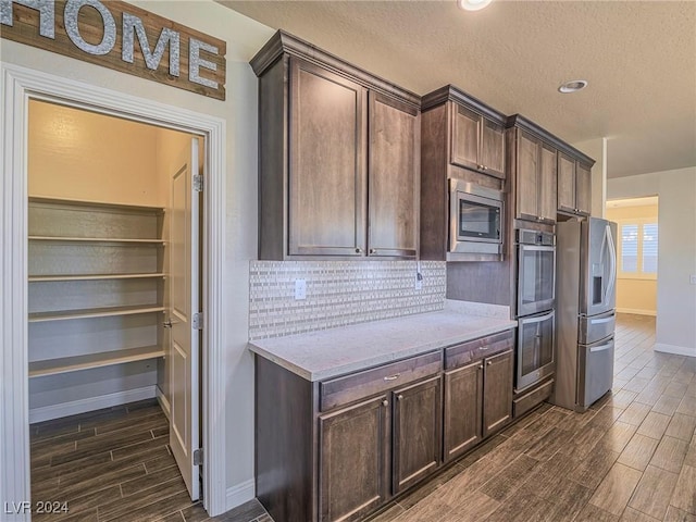 kitchen featuring tasteful backsplash, dark brown cabinets, and appliances with stainless steel finishes