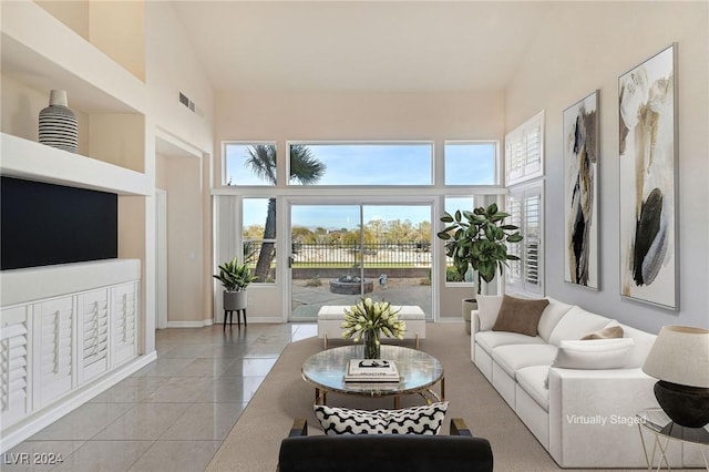 living room featuring a towering ceiling, light tile patterned floors, and a mail area