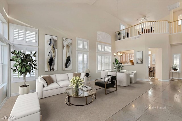 living room with light tile patterned flooring, a towering ceiling, and ceiling fan with notable chandelier