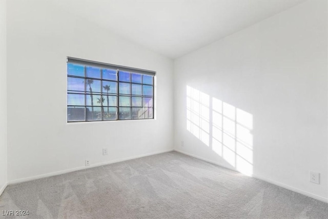 empty room with light colored carpet, vaulted ceiling, and plenty of natural light