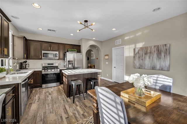 kitchen with a center island, sink, appliances with stainless steel finishes, light hardwood / wood-style floors, and a chandelier