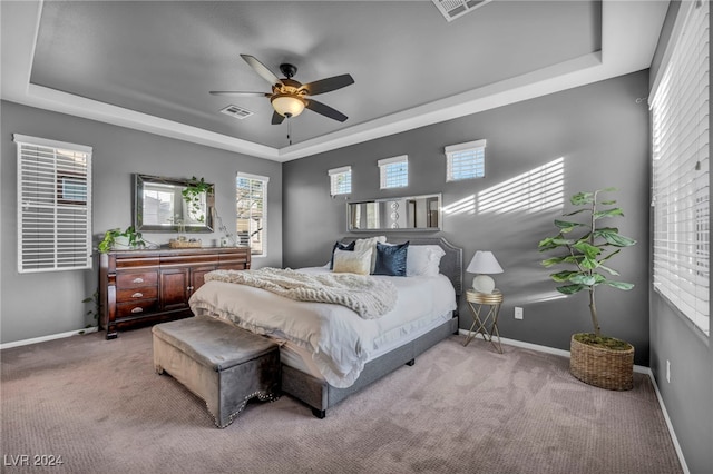 carpeted bedroom featuring ceiling fan and a tray ceiling