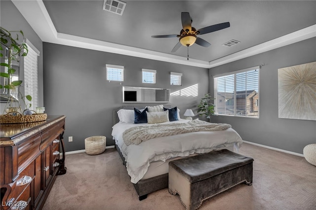 bedroom with ceiling fan, a raised ceiling, and light carpet