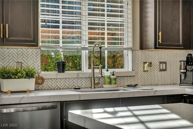 kitchen featuring backsplash, light stone counters, dark brown cabinets, and stainless steel dishwasher