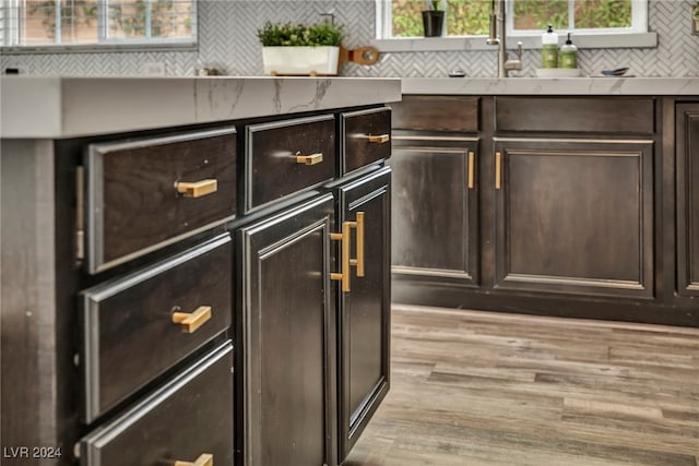 room details featuring decorative backsplash, dark brown cabinets, and light hardwood / wood-style flooring