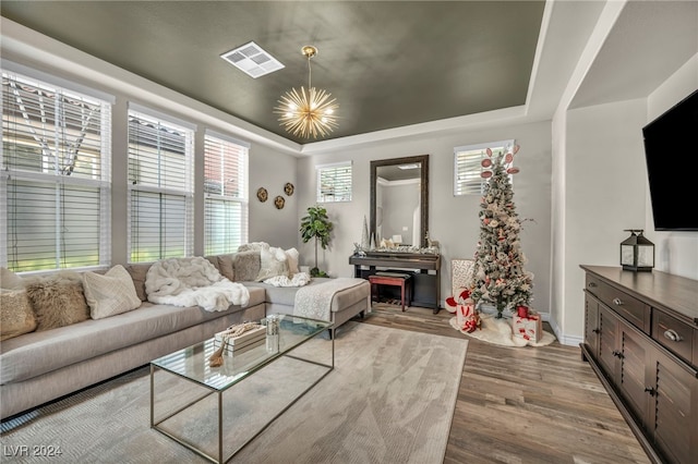 living room featuring a tray ceiling, light hardwood / wood-style flooring, and a chandelier