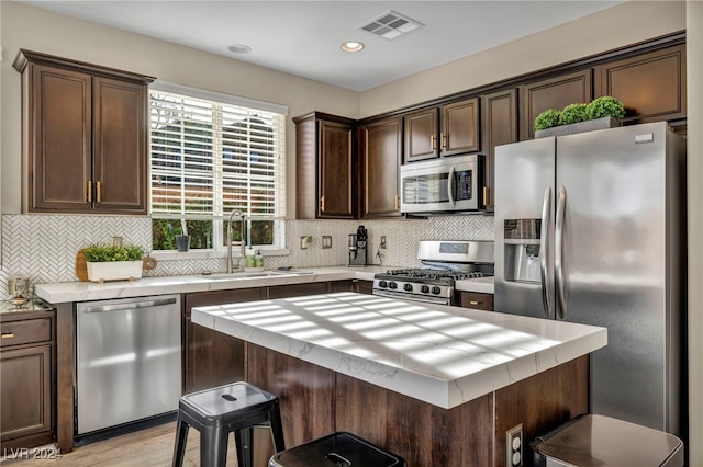 kitchen with a kitchen breakfast bar, sink, stainless steel appliances, and dark brown cabinets