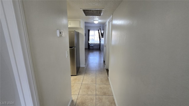 corridor featuring light tile patterned flooring and a textured ceiling