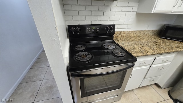 kitchen with light tile patterned flooring, electric range, white cabinets, and light stone countertops