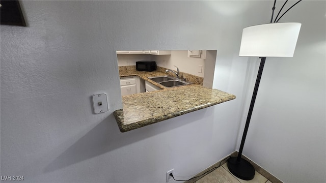 kitchen with white cabinetry, sink, and light tile patterned flooring