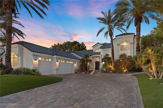 mediterranean / spanish-style house featuring a garage and a yard