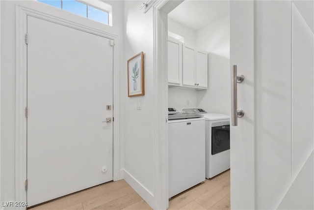 washroom featuring cabinets, washer and dryer, and light hardwood / wood-style flooring