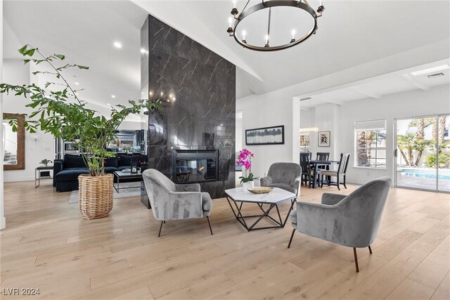 living room featuring a fireplace, light hardwood / wood-style flooring, and a notable chandelier