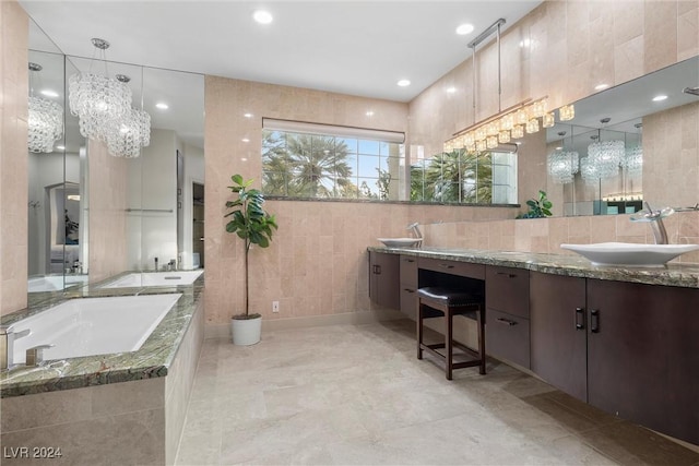 bathroom with tiled tub, vanity, and tile walls