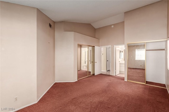 unfurnished bedroom featuring carpet, ensuite bathroom, and vaulted ceiling