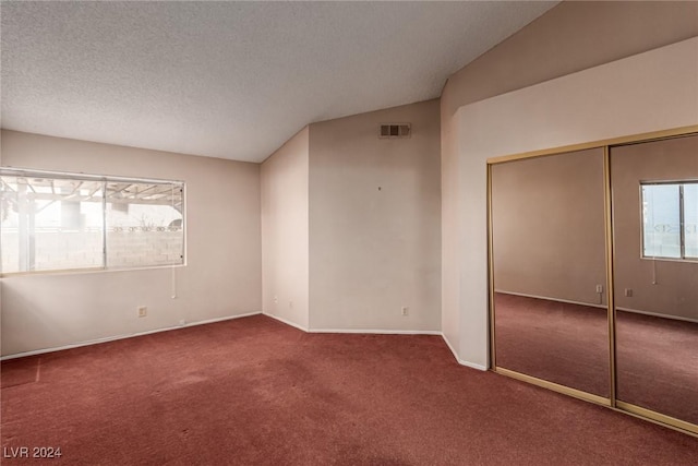 carpeted empty room with lofted ceiling and a textured ceiling