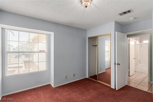 unfurnished bedroom featuring carpet flooring, a closet, and a textured ceiling