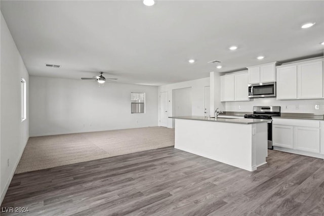 kitchen with wood-type flooring, stainless steel appliances, white cabinetry, and a kitchen island with sink