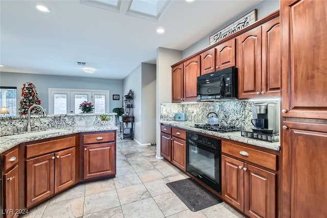 kitchen with light stone countertops, sink, backsplash, light tile patterned floors, and black appliances