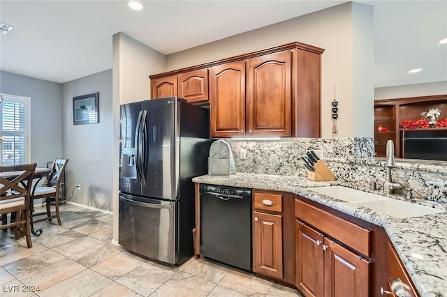 kitchen featuring dishwasher, sink, decorative backsplash, stainless steel fridge, and light stone counters